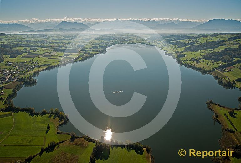 Foto: Der Baldeggersee LU glänzt in der Sonne. Im Hintergrund die Föhnwand über der Alpenkette. (Luftaufnahme von Niklaus Wächter)