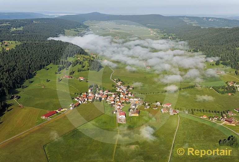 Foto: Das berühmte eiskalte Dörfchen La Brevine im Neuenburger Jura sieht im Sommer sehr einladend aus. Das lokale Hochnebelfeld zeugt vom eigenwilligen Lok. (Luftaufnahme von Niklaus Wächter)