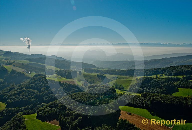 Foto: Blick von den Jurahöhen über das neblige Mittelland zu den Alpen. Links die Wasserdampffahne des Kernkraftwerks Gösgen (SO).. (Luftaufnahme von Niklaus Wächter)