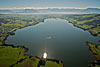 Foto 157: Der Baldeggersee LU glänzt in der Sonne. Im Hintergrund die Föhnwand über der Alpenkette.